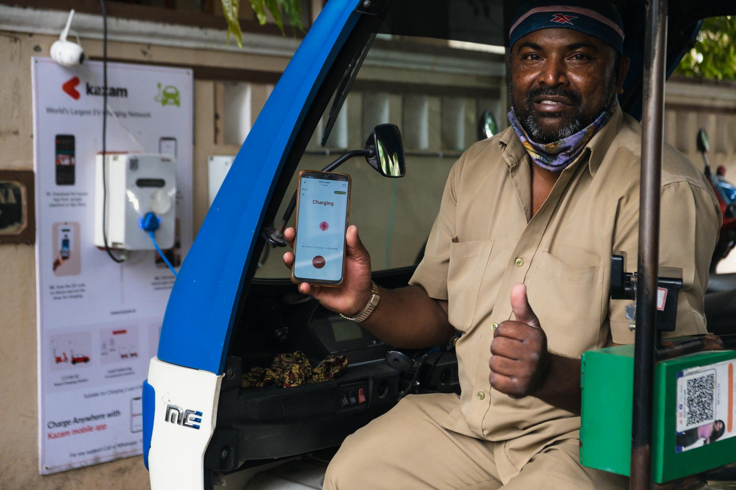 Conducteur utilisant son smartphone à une borne de recharge