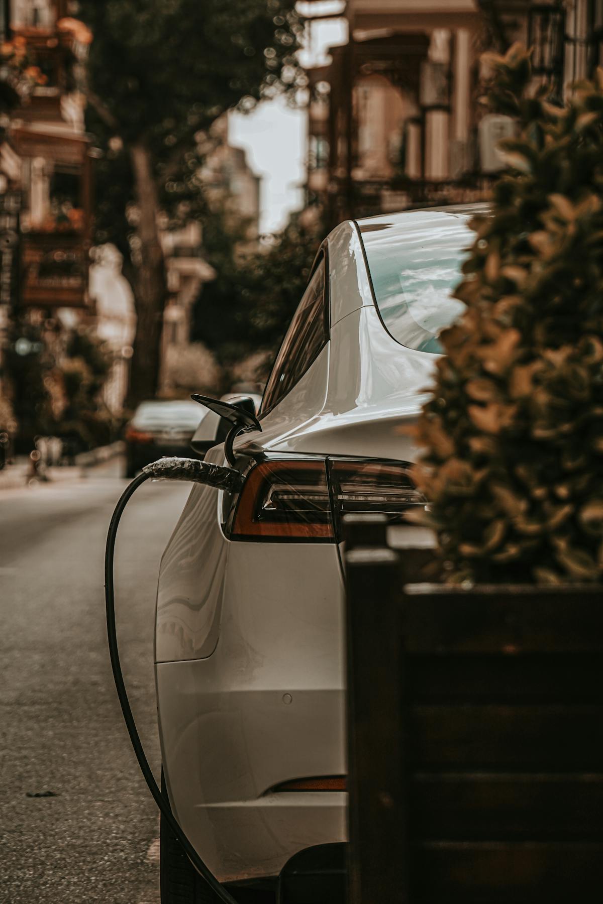 Véhicule électrique en charge dans une rue bordée d'immeubles résidentiels